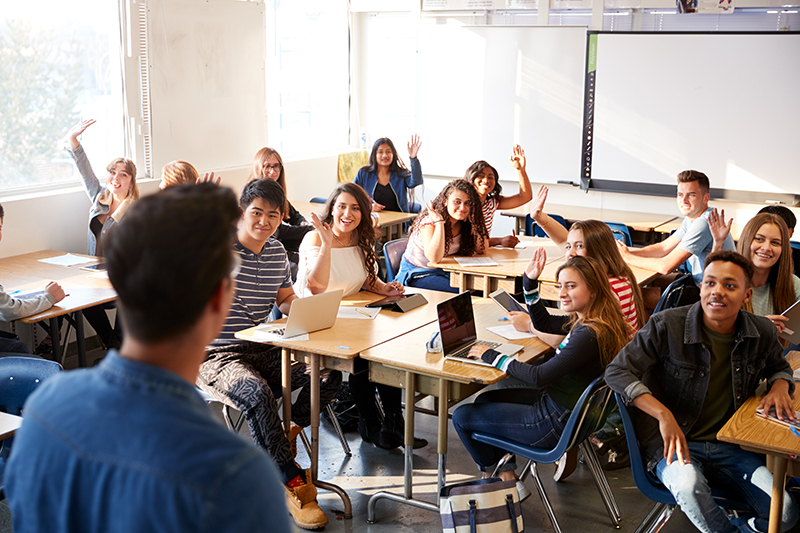 Rear,View,Of,Male,High,School,Teacher,Standing,At,Front