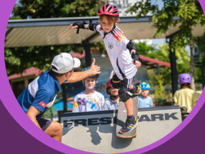 A student skateboarding with support from the PE teacher